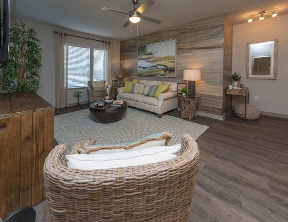 A living room with a wicker sofa and a painting on the wall.