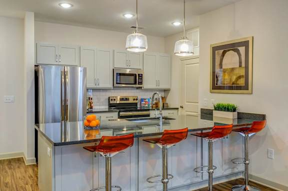 A modern kitchen with a bar area and a fridge.