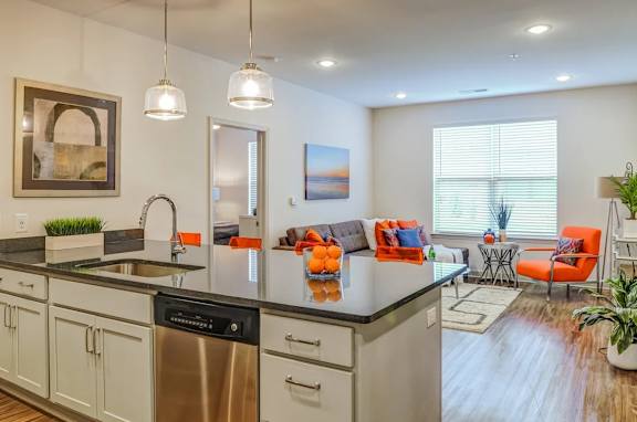 A modern kitchen with a large island and a dining area with orange chairs.