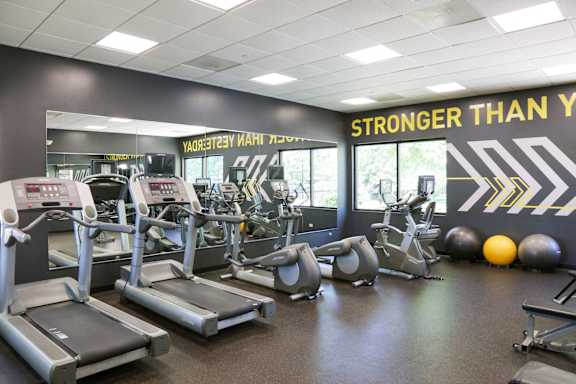 a workout room with cardio equipment and a sign stronger than you on the wall
