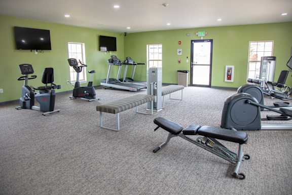 A gym with a variety of equipment including treadmills, exercise bikes, and weight machines.