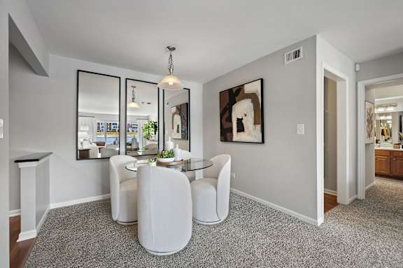 A modern living room with a glass table and white chairs.