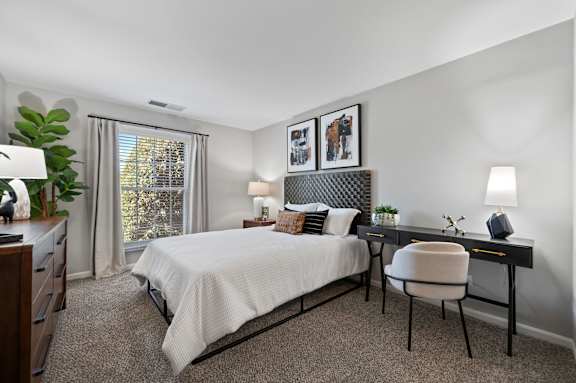 A bedroom with a bed, desk, chair, and window.