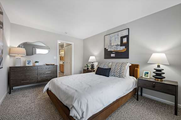 A bedroom with a large bed, a nightstand, and a dresser.