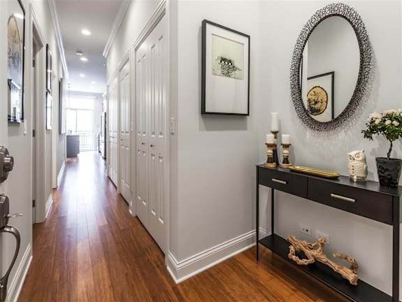 A long hallway with a mirror and a console table with decorations.
