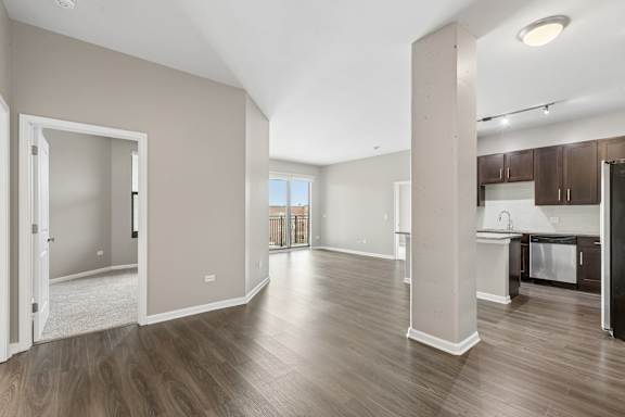 A spacious living room with a kitchen area in the background.