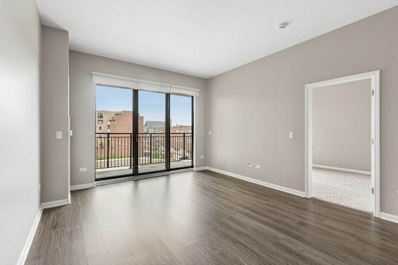 A spacious room with a view of a balcony and buildings outside.
