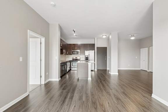 A spacious kitchen with wooden floors and white walls.