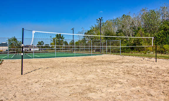 A sandy beach volleyball court with a net and posts.