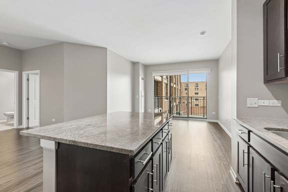 A kitchen with a marble countertop and wooden floors.