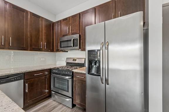 A kitchen with a stainless steel refrigerator, microwave, oven, and dishwasher.