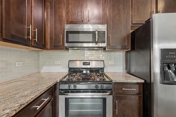 A kitchen with a stove, microwave, and refrigerator.