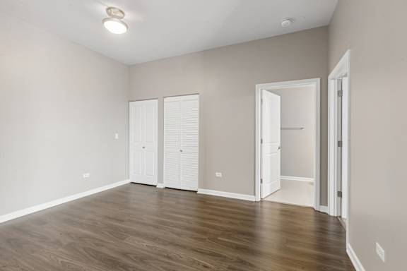A room with white doors and wooden floors.