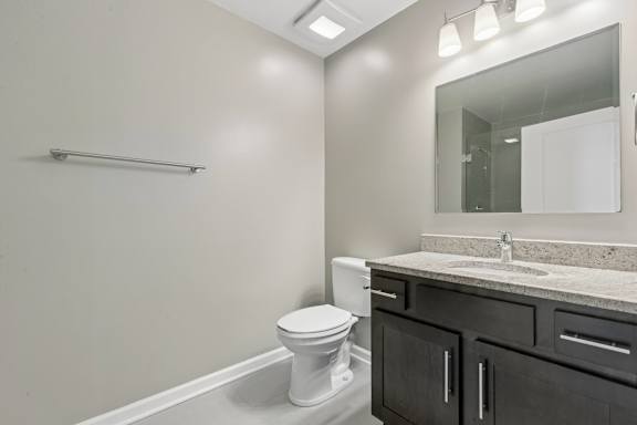 A bathroom with a toilet, sink, and mirror.
