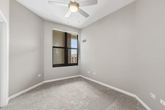 A room with a ceiling fan and a window with blinds.