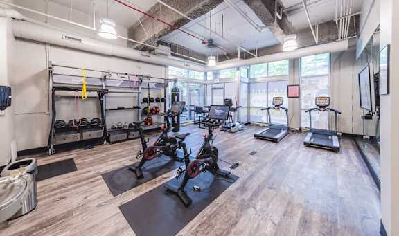 A gym with a variety of exercise equipment including treadmills, stationary bikes, and weight machines.