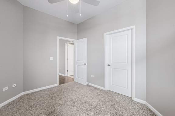 A room with a carpeted floor and two white doors.
