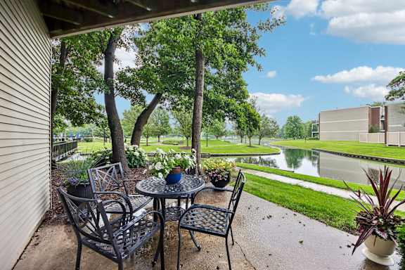 A patio with a table and chairs overlooking a pond.