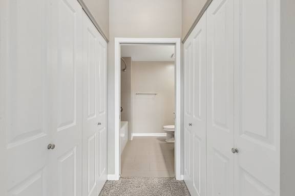 A hallway with white doors on both sides leading to a bathroom.