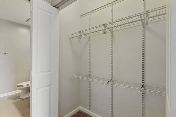 A white closet with a toilet in the background.
