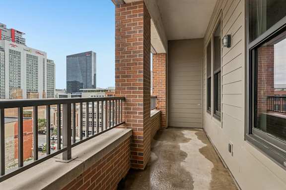 A balcony with a brick pillar and a metal railing.