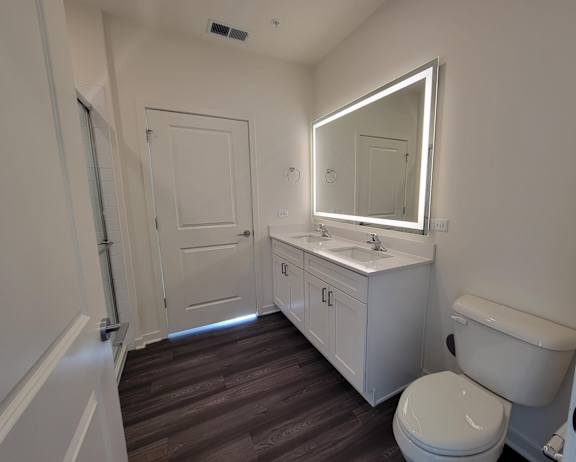 A bathroom with a toilet, sink, and mirror.