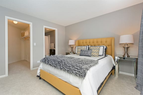 A bedroom with a large bed and a nightstand with lamps at Brookdale Lakes, IL, 60563
