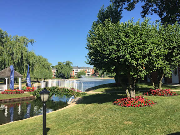 A park with a pond, trees, and flowers.