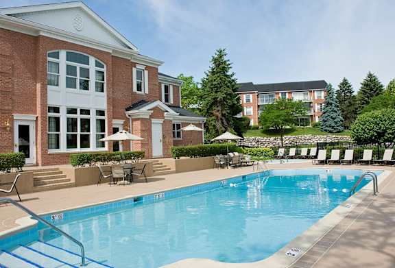 A large swimming pool in front of a brick building.