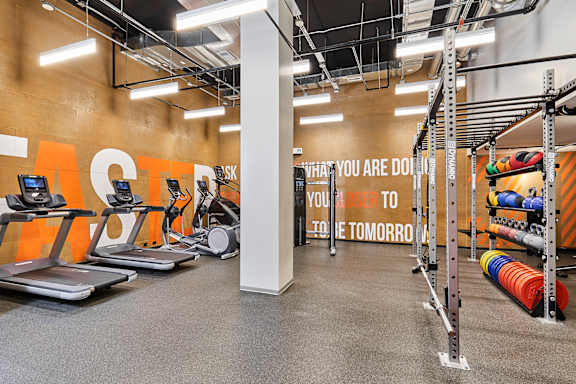 A gym with treadmills, weights, and a motivational quote on the wall.