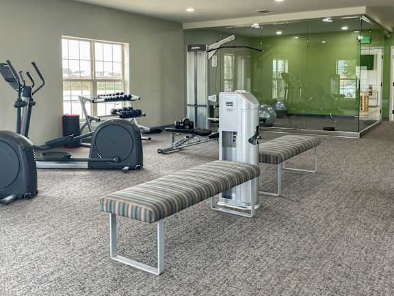A gym with a variety of equipment including treadmills, weights, and exercise balls.