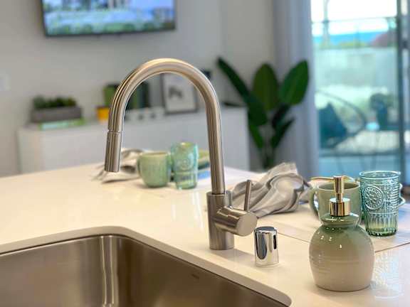 A modern kitchen sink with a chrome faucet and green soap.