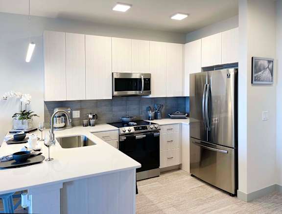 A modern kitchen with white cabinets and stainless steel appliances.
