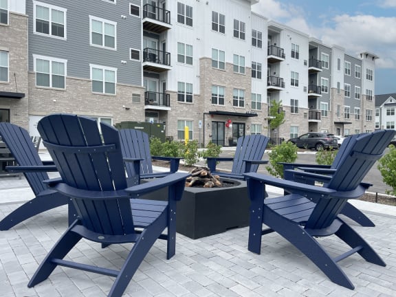 a patio with blue chairs and a fire pit in front of an apartment building at Enclave Crystal Lake Townhomes and Apartments, Crystal Lake, 60014