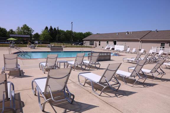 a large pool with chaise lounges and a building in the background at Evergreen Luxury Apartments, Merrillville, IN