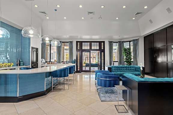A modern kitchen with blue chairs and a black counter.
