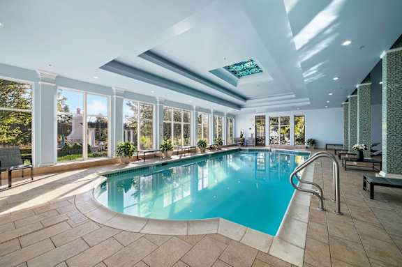 A large indoor swimming pool with a sunny view outside.