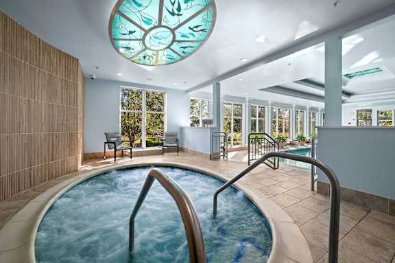 A round glass window with a fish design is above a hot tub.