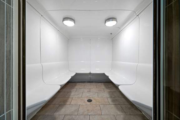 A long, narrow hallway with white walls and a tiled floor.