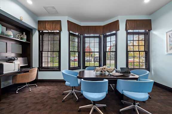 A conference room with a brown table and blue chairs.