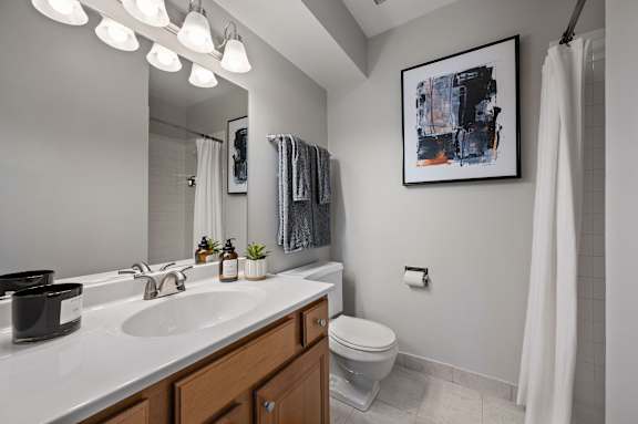 A bathroom with a white sink, toilet, and a painting on the wall.