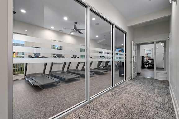 A gym with treadmills and mirrors on the wall.