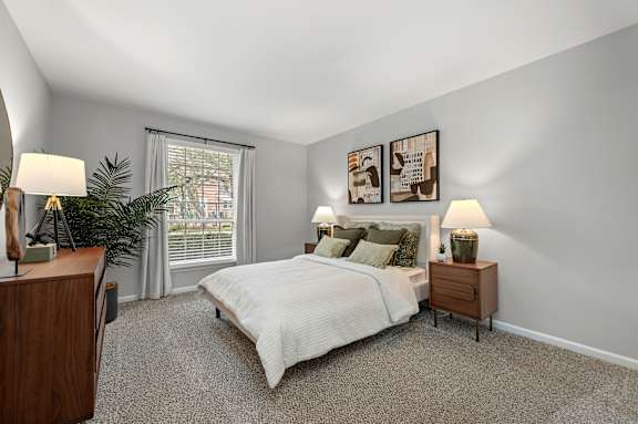 A bedroom with a bed, nightstands, and a plant.