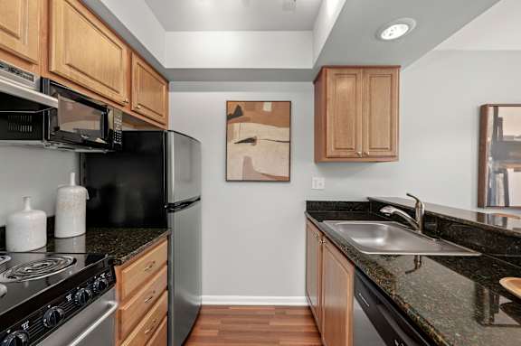A kitchen with black granite countertops and wooden cabinets.