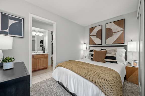 A bedroom with a bed, nightstand, and two wall art pieces.