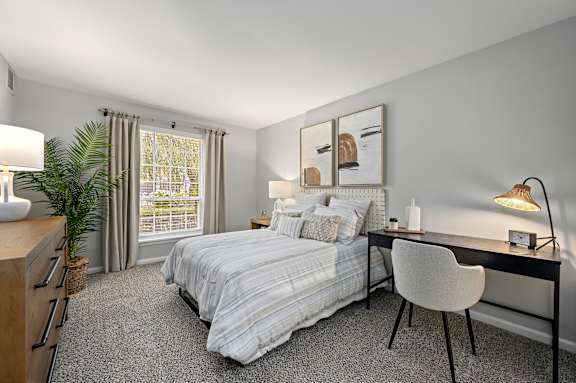 A bedroom with a bed, desk, chair, and window.
