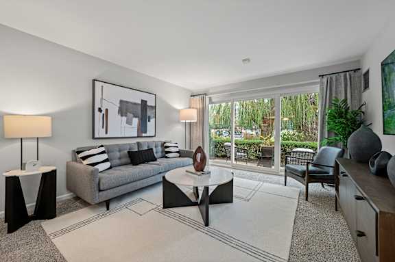 A modern living room with a grey couch, a coffee table, and a painting on the wall.