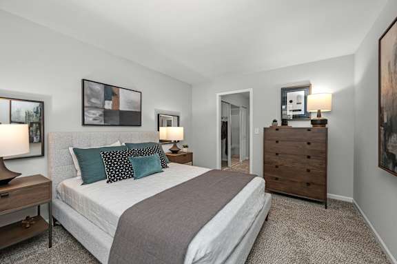 A bedroom with a bed, nightstands, and a painting on the wall.