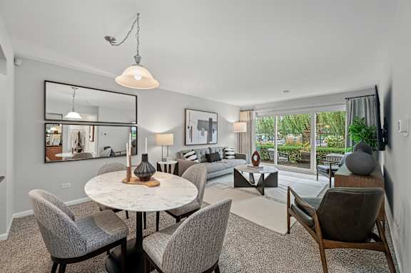 A modern dining room with a round table and grey chairs.
