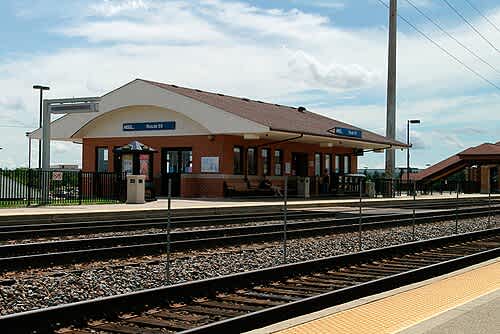 A train station with a blue signboard and a yellow platform.